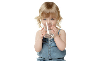 Lovely little girl drinking water, over white